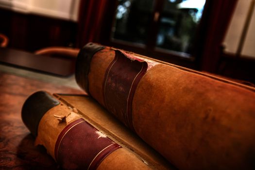 Two old book in a leather cover on wooden table with vintage glasses close-up