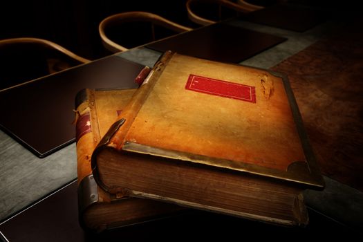 Old book in a leather cover on wooden table with vintage glasses close-up