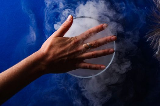 hand over smoking blue glass with blue background