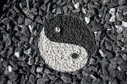 Yin and Yang designed with stone in a outdoor garden surrounding the sign