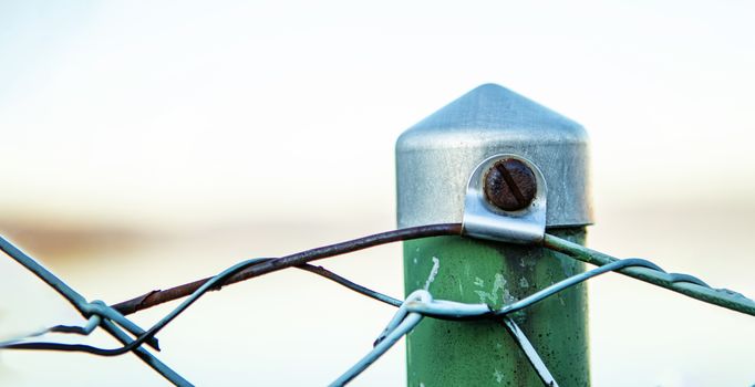 closeup of a fence pole with a rusty screw and green color in banner layout with space for copy