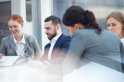 Business team sitting by the table with laptop and documents in office