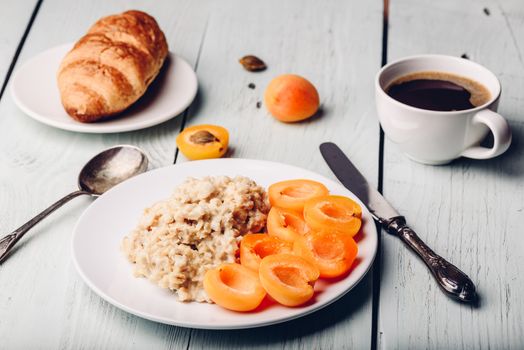 Breakfast set. Porridge with sliced apricot, cup of coffee, glass of grapefruit juice and croissant