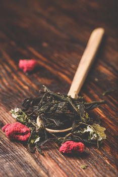 Wooden spoon of raspberry herbal tea over wooden table