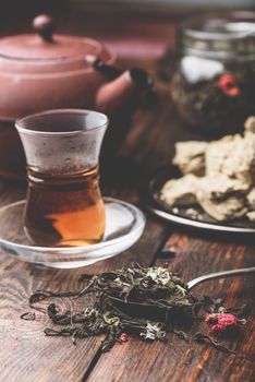 Spoonful of raspberry herbal tea and ready tea in armudu glass with plate of sunflower halva