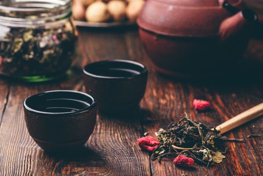 Cast iron tea bowls with teapot and wooden spoonful of raspberry herbal tea