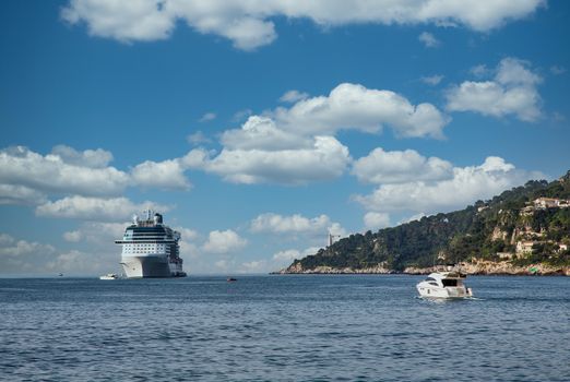 A white yacht approaching a luxury cruise ship on the coast of France