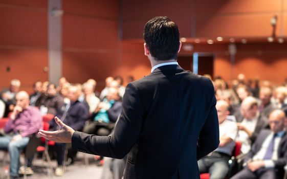 Speaker at Business Conference with Public Presentations. Audience at the conference hall. Entrepreneurship club. Rear view. Panoramic composition. Background blur.