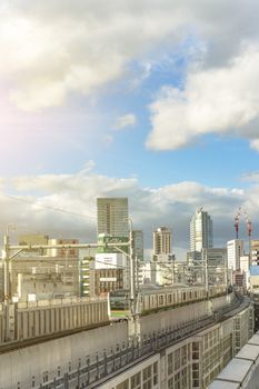 kanda station where the trains of the yamanote line pass between the top of the buildings of the district of Chiyoda under the blue sky of Tokyo.