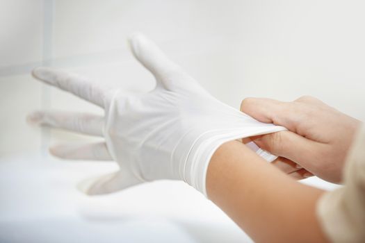 Hands of human taking on rubber gloves