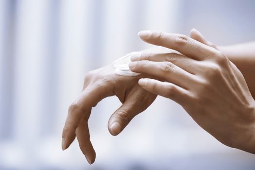 Woman applying moisturizing cream on hands