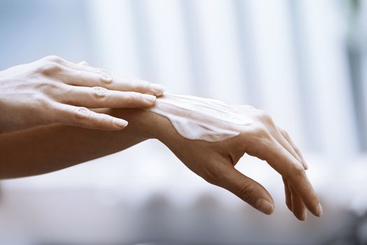 Woman applying moisturizing cream on hands