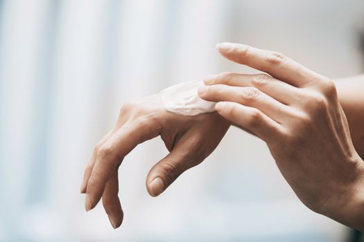 Woman applying moisturizing cream on hands