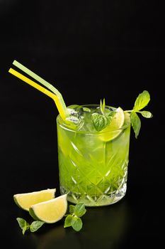 Mojito cocktail in a glass glass with lime on a plain black background