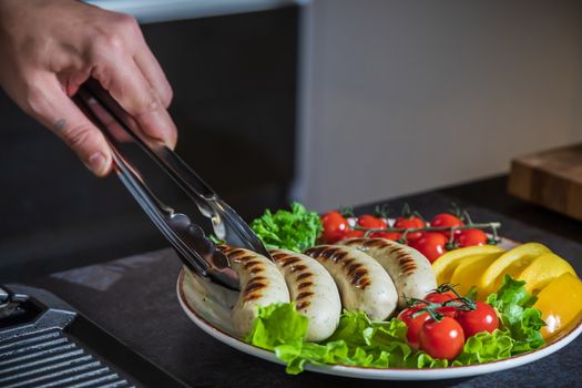 Appetizing grilled chicken sausages on a plate with herbs and vegetables