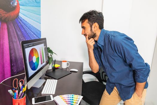 Young bearded man pointing at computer. Business employee working serious and concentrated.