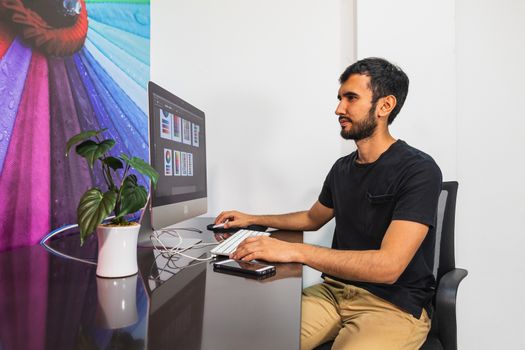 Bearded man in a casual wear sitting at the computer