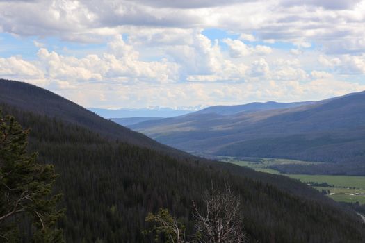 A view of the grassy covered Colorado mountains and blue cloudy skies 