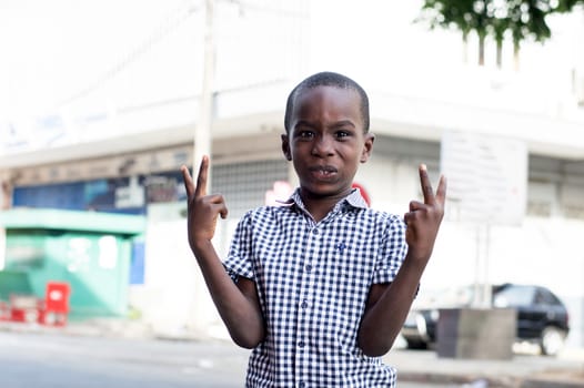 Happy little boy standing out by making signs of victory.