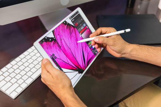 Close Up view. Man sitting in office at table and is using a tablet. Man Drawing