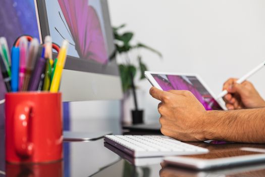 Close Up view. Man sitting in office at table with stationary and is using a tablet. Man Drawing