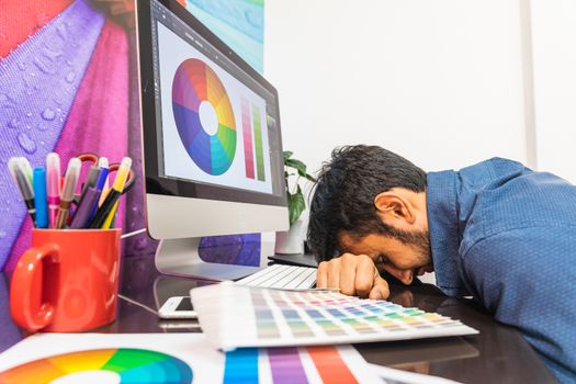 Sleeping young man working on computer. The designer works in the later time. A young man sits at the computer