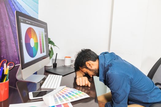 Sleeping young man working on computer. The designer works in the later time. A young man sits at the computer