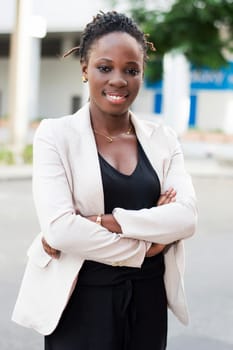 Portrait of beautiful smiling businesswoman standing with arms crossed outdoors.