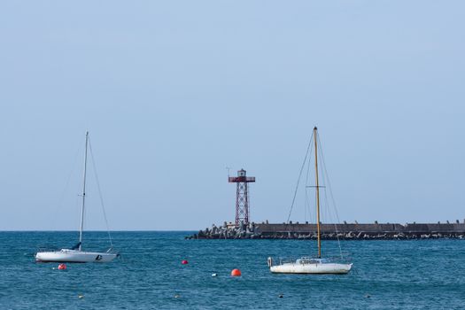 Sailing boats anchored in the bay with harbor lighthouse beacon, Mossel Bay, South Africa