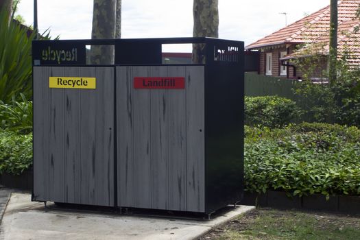 Local council bin enclosure for recycled waste and landfill waste disposal in a park