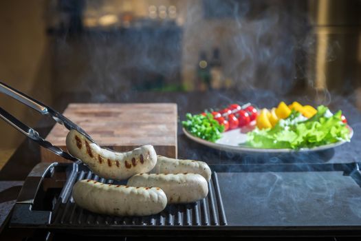 A cook turns over tongs of chicken to a grilled surface