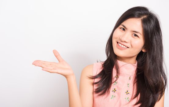 Portrait Asian beautiful young woman standing, She showing hand to presenting product and looking at the camera, shoot photo in a studio on white background, There was copy space