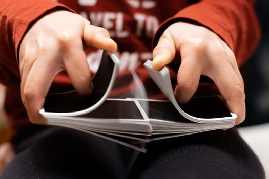 A person shuffling a deck of playing cards with a good color contrast between red and black colors.