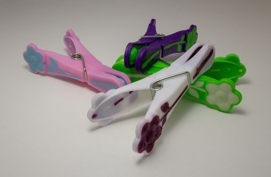 Four clothespins of different colors on the top of a white table