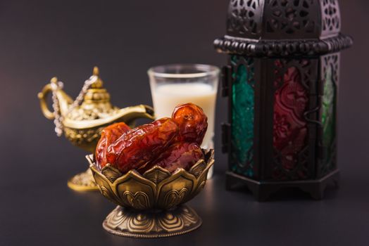 Ramadan Kareem fasting Food Concept, Bronze plate dates, milk, and lantern Aladdin lamp decoration, eid Arabian Muslim religious festival on a black background with copy space for text