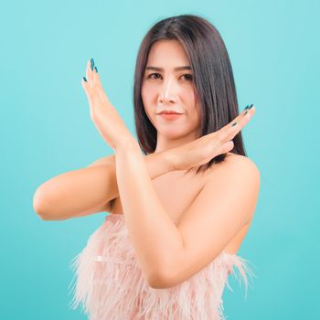 Asian beautiful woman her showing say no hand sign looking to camera on blue background, with copy space for text