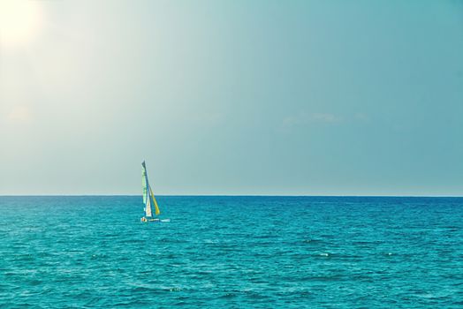 Small personal sailboat sailing in the open flat sea on a summer day. Calm seascape with blue sky. Sunny day in the mediterranean sea at Tel Aviv city. Copy Space view.