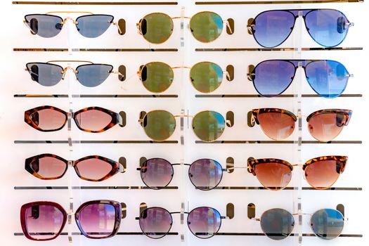 Stand with many sunglasses in a store of optics. Front close up view.