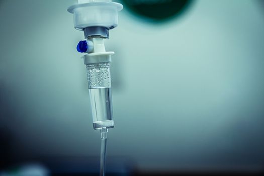 Set IV fluid intravenous drop saline drip in a hospital room. Close up, dark blue light background, selective focus and copy space.