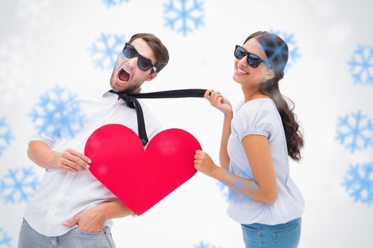 Brunette pulling her boyfriend by the tie holding heart against snowflakes