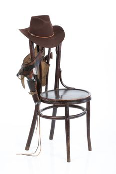 Cowboy belt, guns and hat on an old chair on isolated background