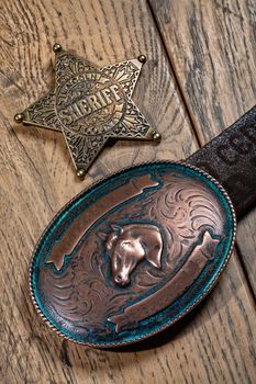 Sheriff's star and copper buckle on a wooden background