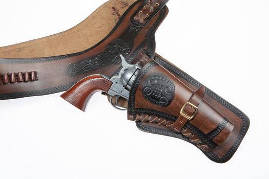 Leather cowboy holster and revolver on an isolated studio background