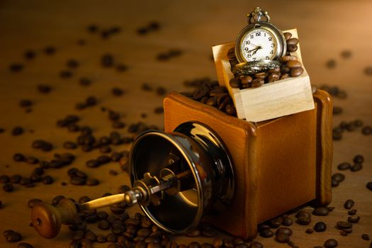 Coffee bean and pocket watch. Manual grinder on table in morning. Concept of coffee time.