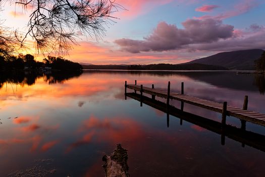Scenic sunset and beautiful reflections on Wallaga Lake with old timber jetty in view.  Australia