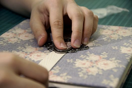 the process of handmade creating of the diary from special scrapbooking paper, paper flowers and other decorative elements