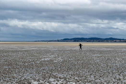 A woman maintaining social distancing walking outdoors on the beach in Dublin, Ireland