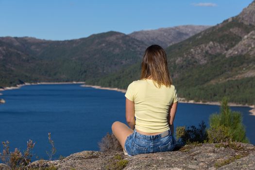 Young happy woman at the mountain, relaxing and enjoying the lake at Geres, Portuguese National Park