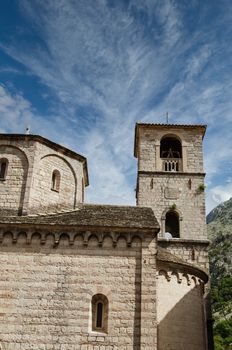Old stone church and bell tower under blue sky in Kotor, Montenegro