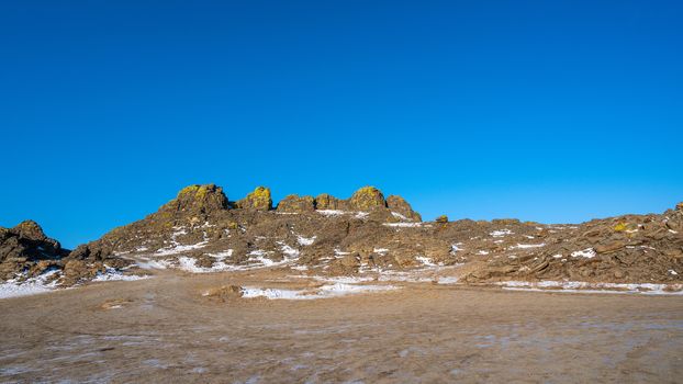 The rocky mountains are covered with snow. The blue color of the sky contrasts with the brown color of mountains and ground. Beautiful scenery of mountains and skies. Lake Baikal, Russia. 